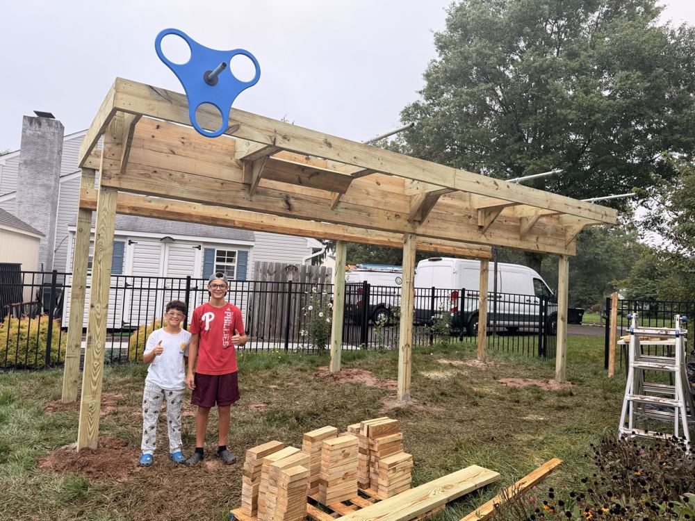 Two kids giving a thumbs up in front of a new ninja rig frame with a blue spinning grip on top
